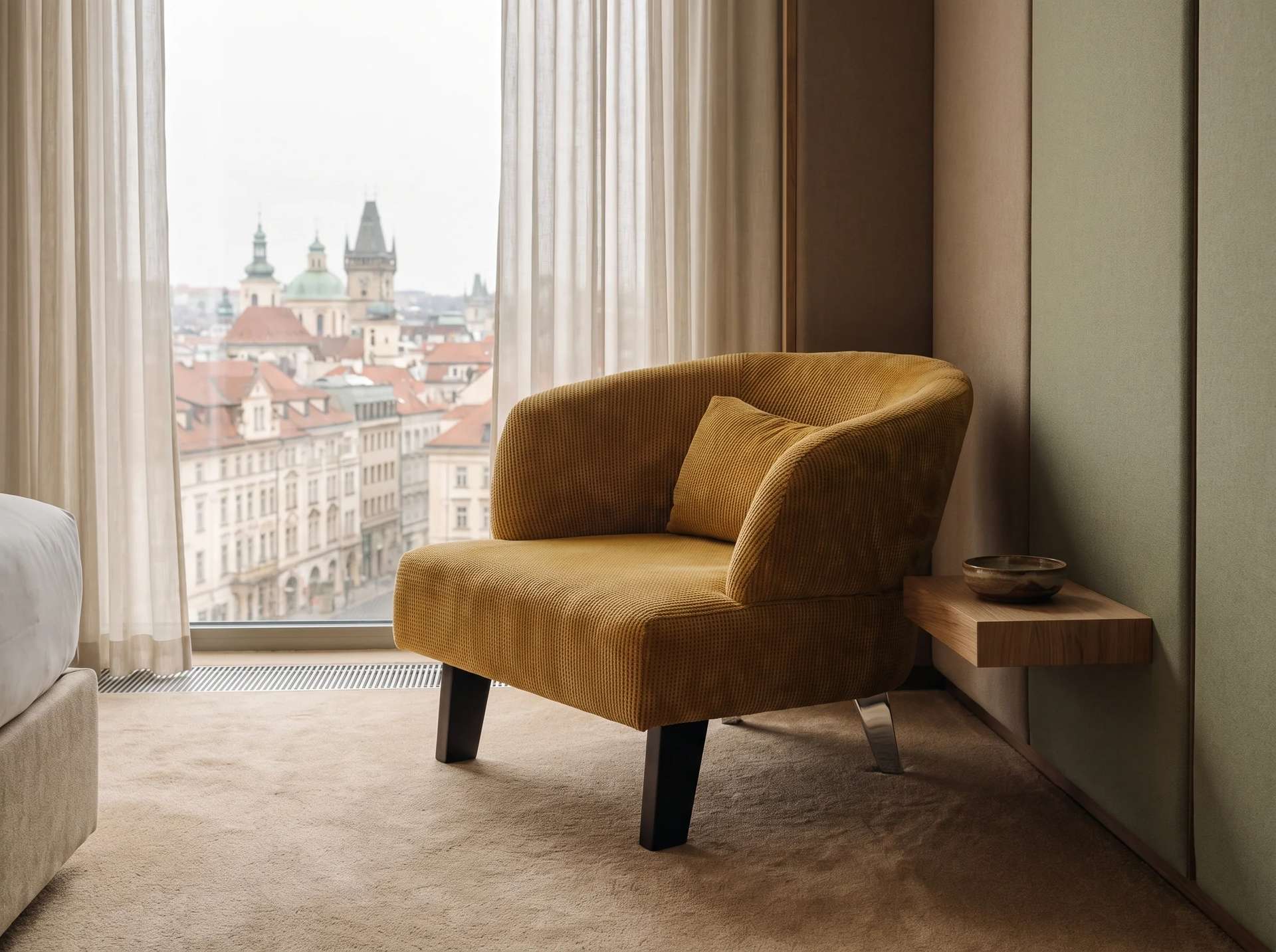 Berlin berjer, hardal sarısı fitilli kadife, serbest sırt yastığı ve koyu ahşap ayaklar, otel süiti yatak odasında